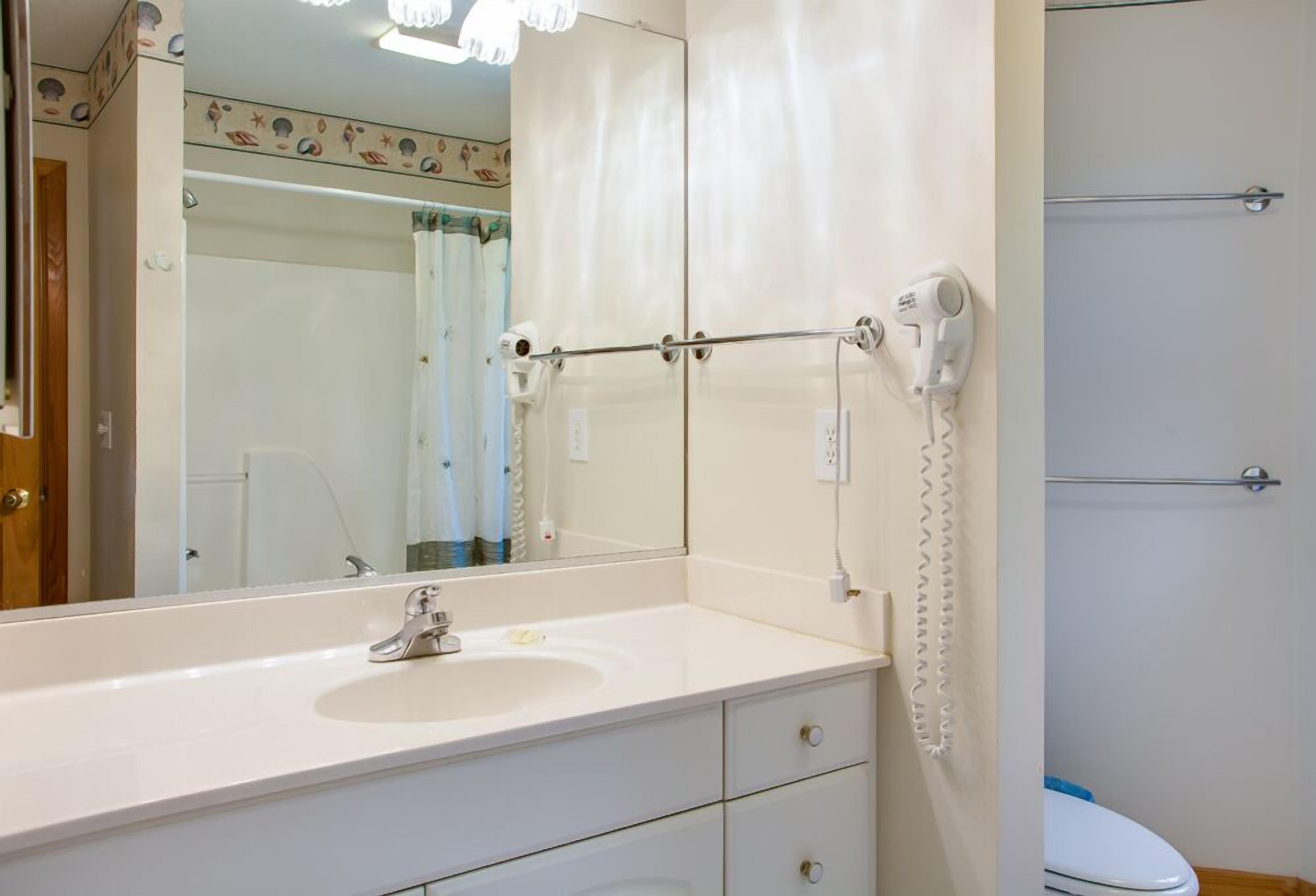 A bathroom with a white sink, a mirror, a towel rack, and a toilet.
