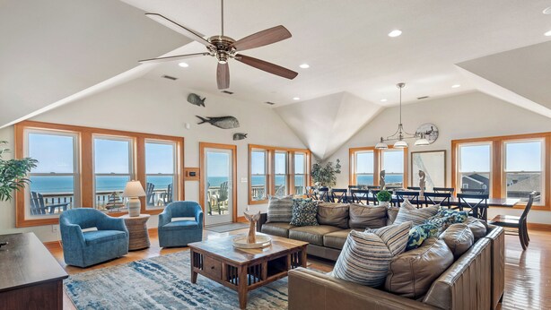 Ein geräumiges Wohnzimmer mit hohen Decken, großen Fenstern und Blick auf das Meer.