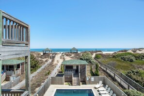 A beachside resort with wooden structures, a pool, and a view of the ocean. - Pompano: Oceanfront Home w/ Private Heated Pool, Hot Tub & Cabana Service (Nags Head)
