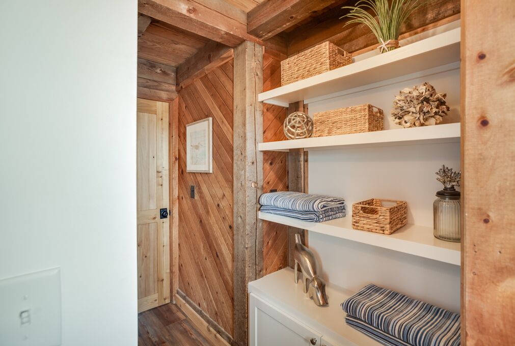 A wooden interior with shelves holding baskets, a vase, and a framed picture.