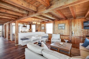 Un vaste espace de vie doté d’un plafond en bois, d’un coin cuisine et d’un espace salon avec un canapé et une table basse.