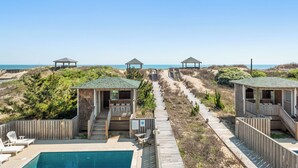 A beachside resort with wooden cabins, a pool, and a boardwalk leading to the beach. - Cobia: Oceanfront Home w/ Private Heated Pool, Hot Tub & Cabana Service (Nags Head)