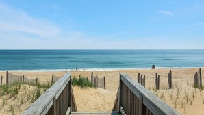 A wooden boardwalk leading to a sandy beach with the ocean in the background. - Cobia: Oceanfront Home w/ Private Heated Pool, Hot Tub & Cabana Service (Nags Head)