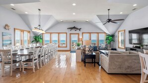 A spacious living area with a dining table, seating, a sofa, and a ceiling fan. - Cobia: Oceanfront Home w/ Private Heated Pool, Hot Tub & Cabana Service (Nags Head)