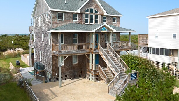 A two-story building with a balcony, a staircase, and a sign indicating it is a vacation rental. - Salt Shaker: Semi-oceanfront, Private Pool, Spa (Nags Head)