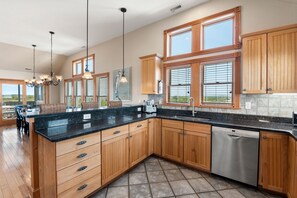 Enjoy cooking and entertaining in this well-equipped kitchen with a central island, ample storage, and large windows offering views of the surrounding landscape.