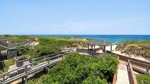 A wooden boardwalk leading to a beach with a gazebo and a view of the ocean. - Sea-Duced: Oceanfront, Great Views, Shared Pool. (Nags Head)