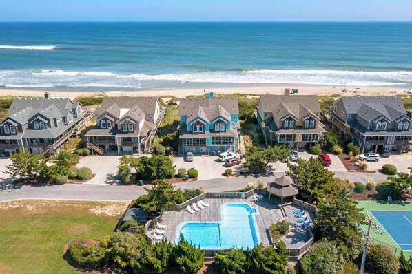 A coastal hotel with multiple houses, a swimming pool, and a tennis court.