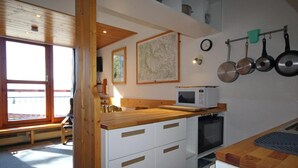 Une cuisine de taille réduite avec des meubles blancs, un plan de travail en bois, un four à micro-ondes et une cuisinière.
