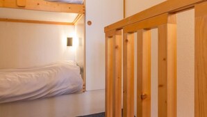 Une chambre avec un lit superposé et une porte en bois.
