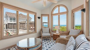A spacious room with large windows, a ceiling fan, wicker furniture, and a view of the ocean. - Favorite Place: Oceanfront, Private Pool, Spa (Nags Head)
