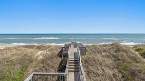 Une promenade en bois qui mène à la plage et offre une vue dégagée sur l’océan.
