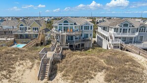 Une propriété située en bord de mer, comprenant plusieurs maisons, une piscine et une terrasse en bois.