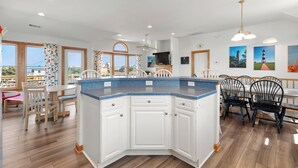 Une cuisine spacieuse dotée d’un grand îlot central, de meubles blancs et offrant une vue sur la ville.