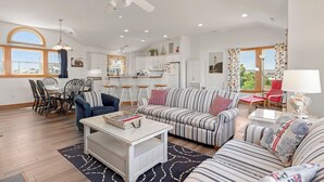 Un salon spacieux comprenant un canapé, des fauteuils, une table basse et un coin repas avec des chaises et une table.