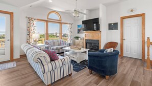 Un salon spacieux avec un canapé, des fauteuils, une table basse et une cheminée.