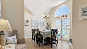 A dining area with a round table, chairs, and a chandelier. - A Change In Latitude: Pet-friendly! Shared Pool, Private Hot Tub (Nags Head)