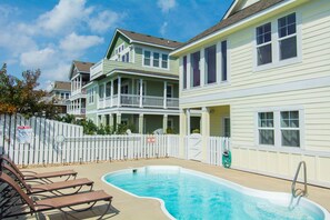 A residential area with a swimming pool, white fences, and houses with balconies. - Hook, Wine And Sinker: Private Pool, Hot Tub, Free Community Amenities! (Corolla)