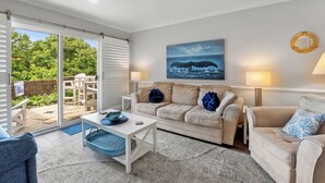 Ein Wohnzimmer mit einem beigen Sofa, einem weißen Couchtisch und einem Wandbild eines Wals.