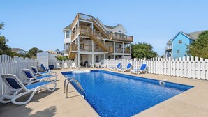 A swimming pool with lounge chairs and a multi-level building in the background. - Ebbtide: Private Pool, Screened Porch, Ocean Views (Corolla)