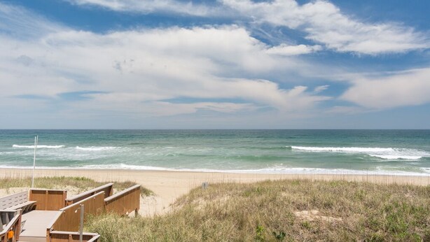 Una playa con estructuras de madera, una orilla arenosa y el océano.