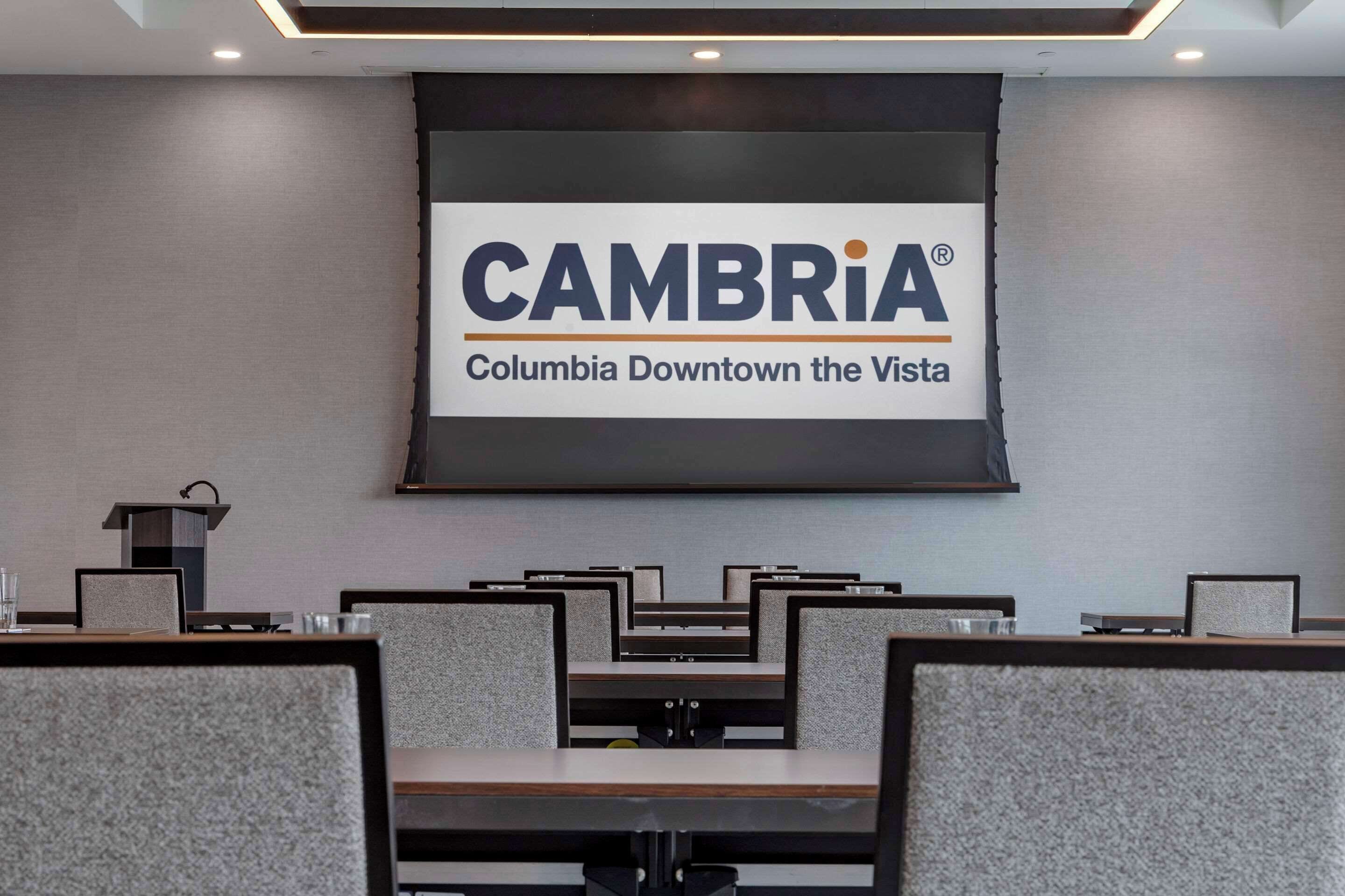 A conference room with a large screen displaying the CAMBRIA® logo and the text "Columbia Downtown the Vista".