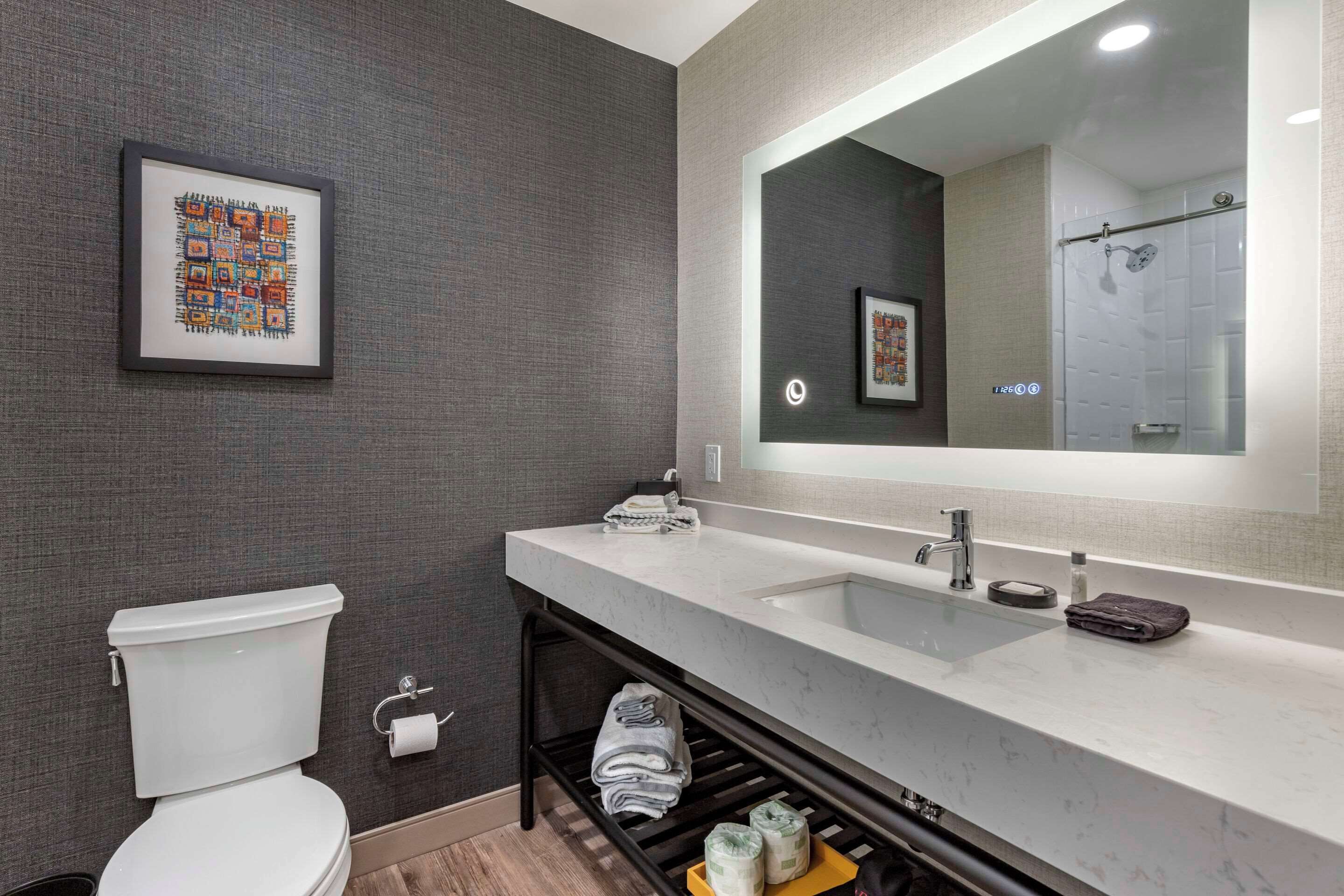 Un baño moderno con inodoro, lavabo y espejo.