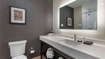 Un baño moderno con inodoro, lavabo y espejo.