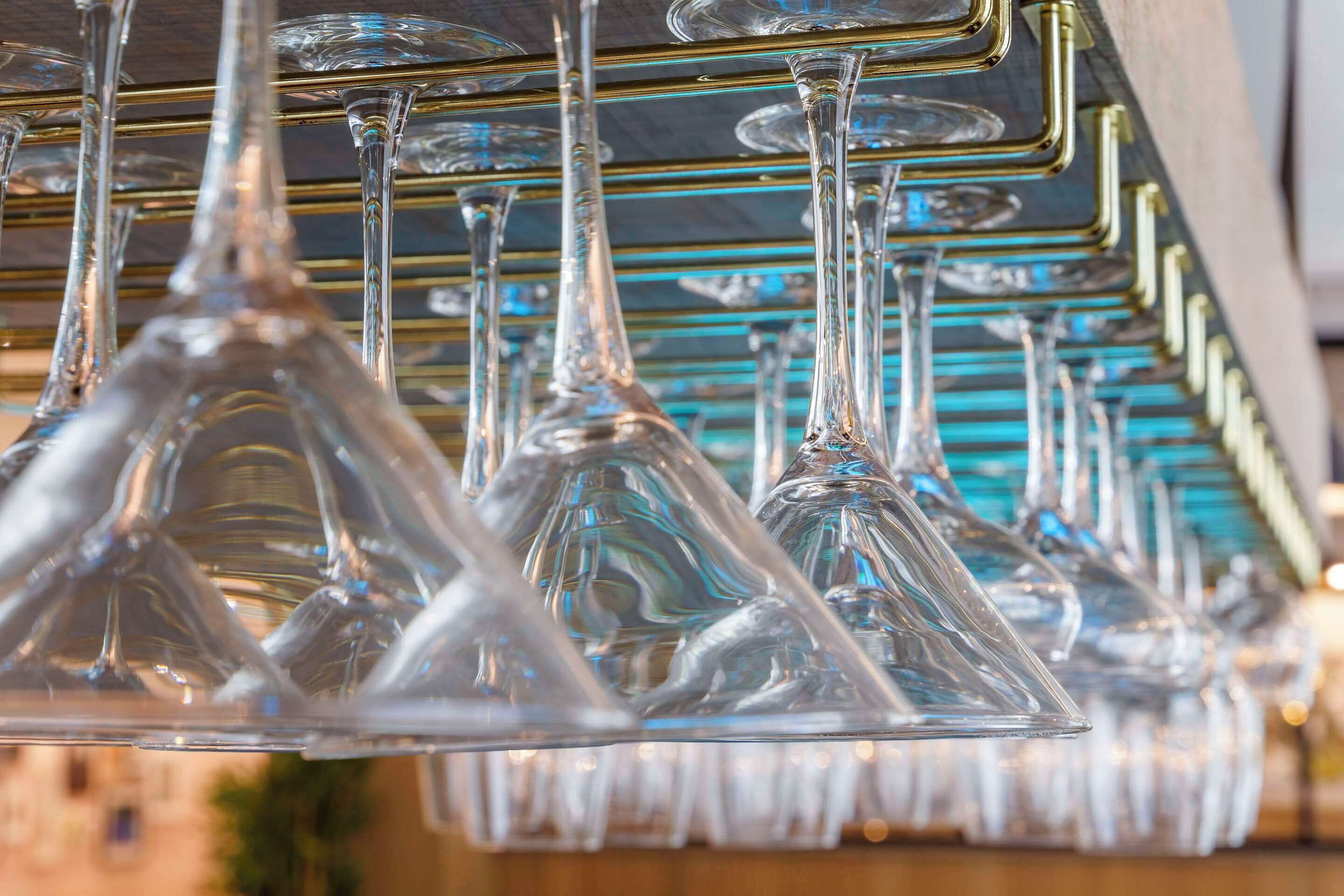 A row of clear glass wine glasses hanging from a metal rack.