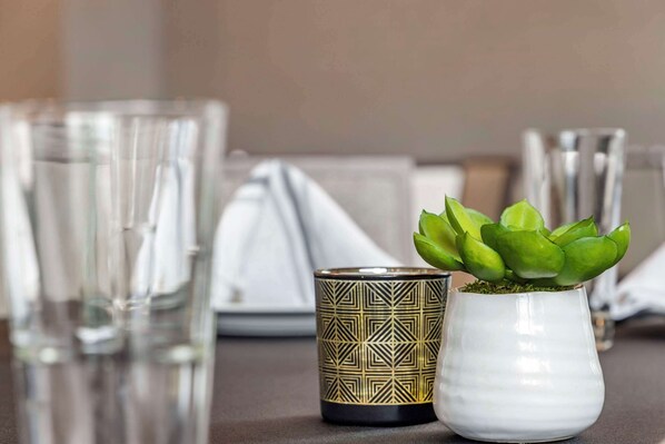 Una mesa con vasos transparentes, un candelabro decorado y una suculenta en maceta.