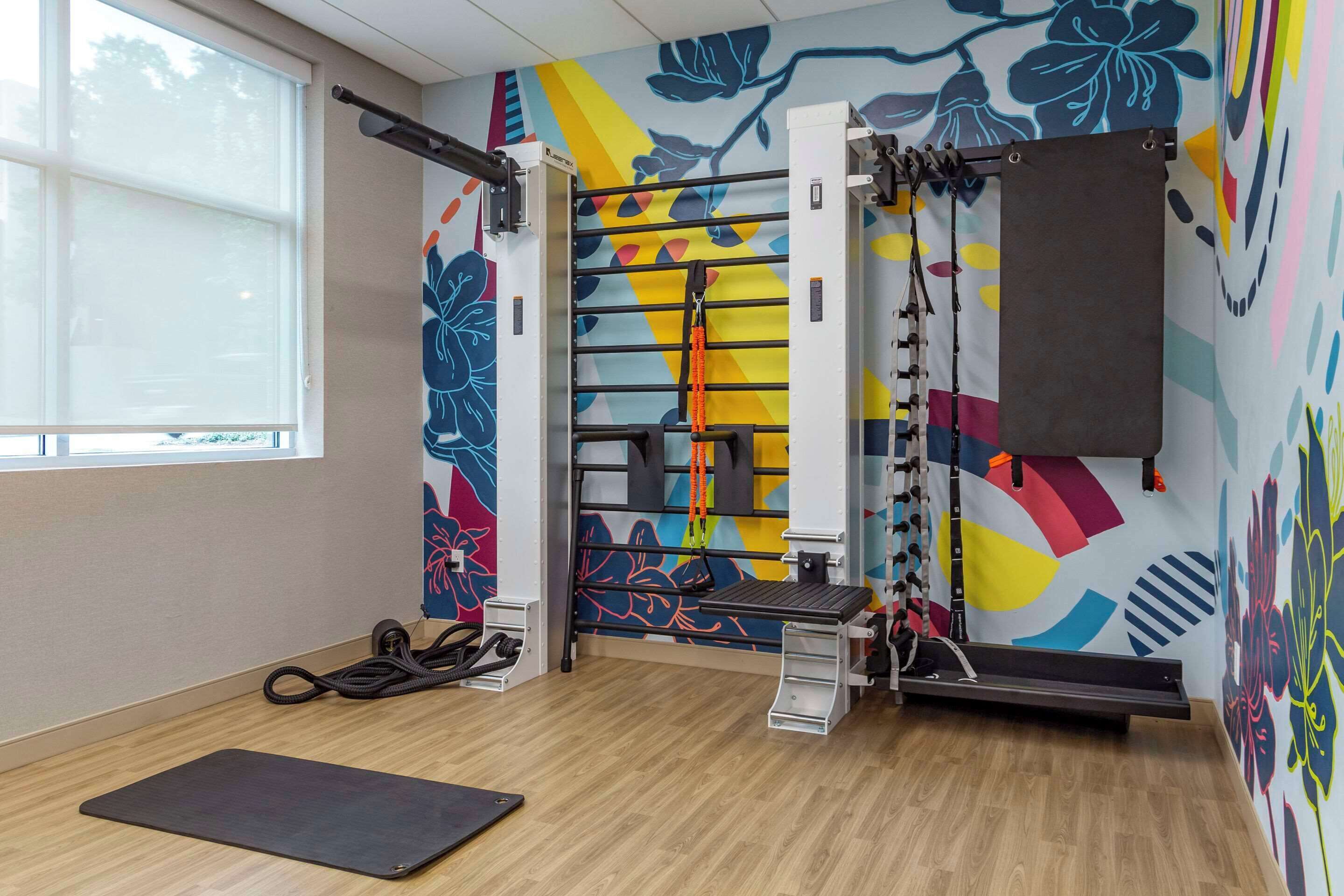 A gym with a pull-up bar, a bench, and a yoga mat.