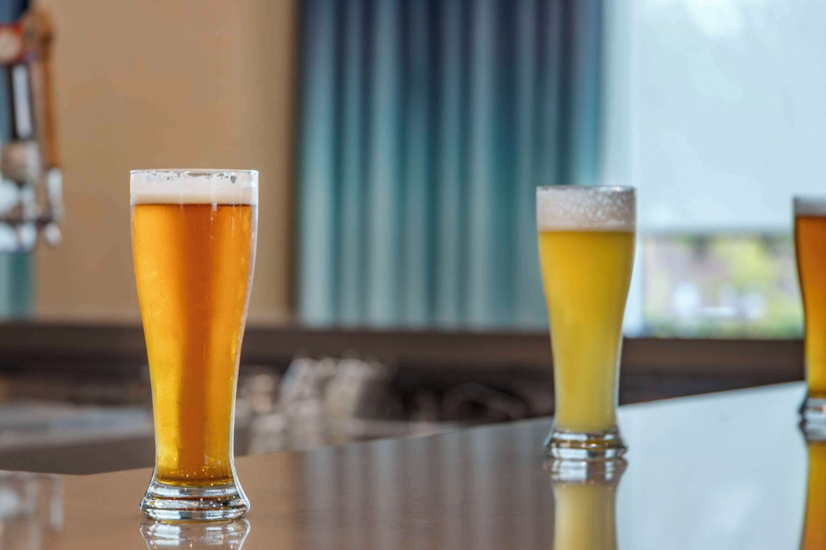 Three glasses of beer on a bar counter.