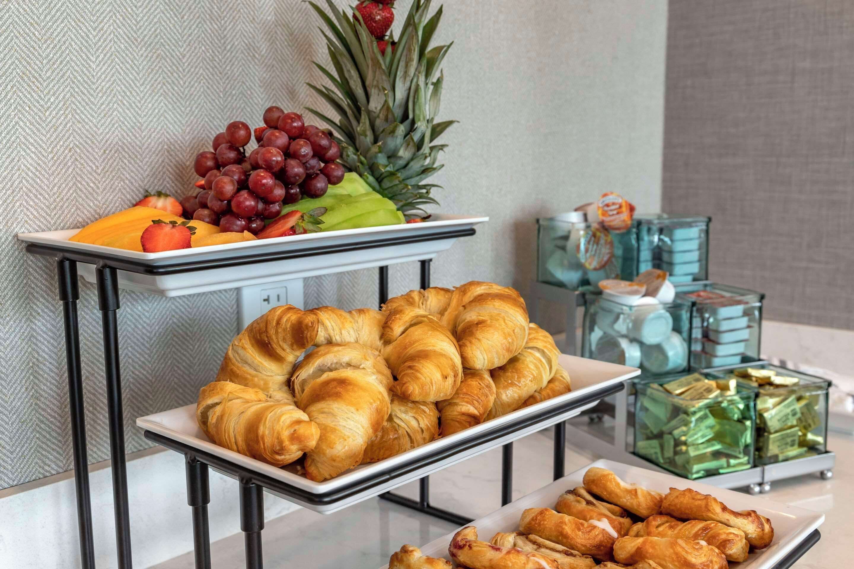 A buffet with pastries, fruits, and a pineapple.