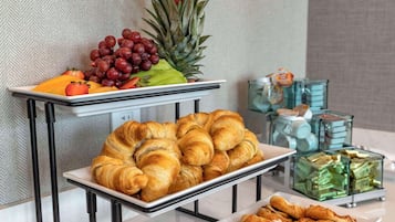 A buffet with pastries, fruits, and a pineapple.