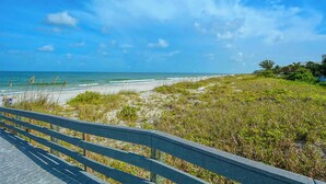 A beach view with a wooden boardwalk leading to the shore. - You and Me and the Sea: 2  BR, 2  BA Condominium in Indian Rocks Beach, Sleeps 4 (Indian Rocks Beach)