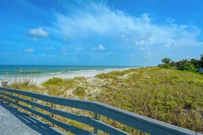 A beach view with a wooden boardwalk leading to the shore.