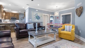 A spacious living room with a dark brown leather sofa, a yellow armchair, and a wooden coffee table. A ceiling fan and recessed lighting are visible. - Great Cottage~Perfect Destination for an amazing Vacation!!! (Gulf Shores)