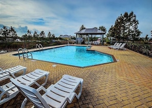 Una piscina rectangular con un mirador y sillas de descanso.