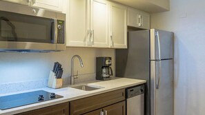 Compact kitchen with modern appliances, sink, dishwasher, microwave, coffee maker, and refrigerator.