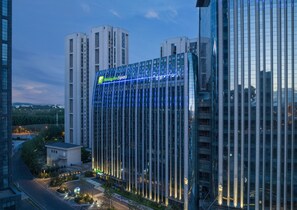 A modern hotel with a prominent glass facade and a visible sign for Holiday Inn Express. - Holiday Inn Express Changchun Ecological Square by IHG (Changchun)