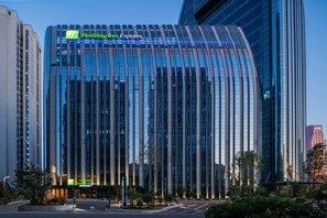 Un hôtel Holiday Inn Express moderne, doté d’une façade incurvée et de grandes fenêtres verticales en verre.