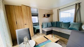 Ein modernes Wohnzimmer mit einer Couch, Sesseln, einem Esstisch und Blick auf die Stadt.