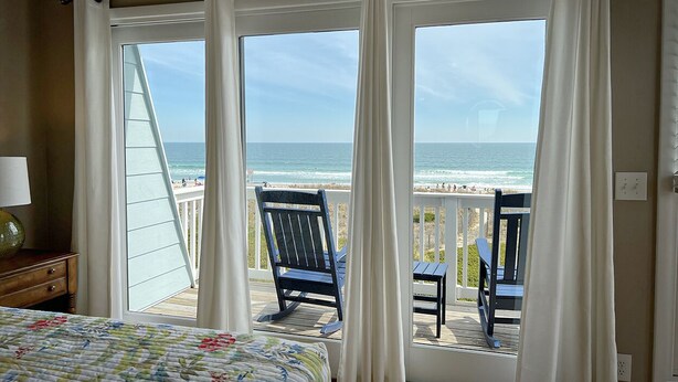 A bedroom with a large window overlooking a beach.