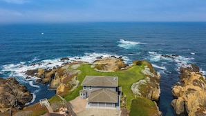A coastal property with a house surrounded by rocky terrain and ocean views.