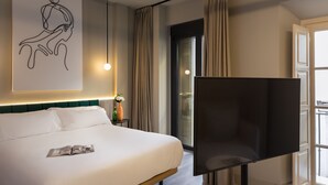 A hotel room with a large bed, a flat-screen TV, a modern art piece, and a large window with curtains. - Coeo Peña Design Apartments (Málaga)