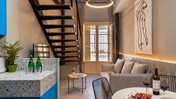Una cocina moderna con una isla integrada, una escalera y un comedor con una mesa dispuesta para dos personas.
