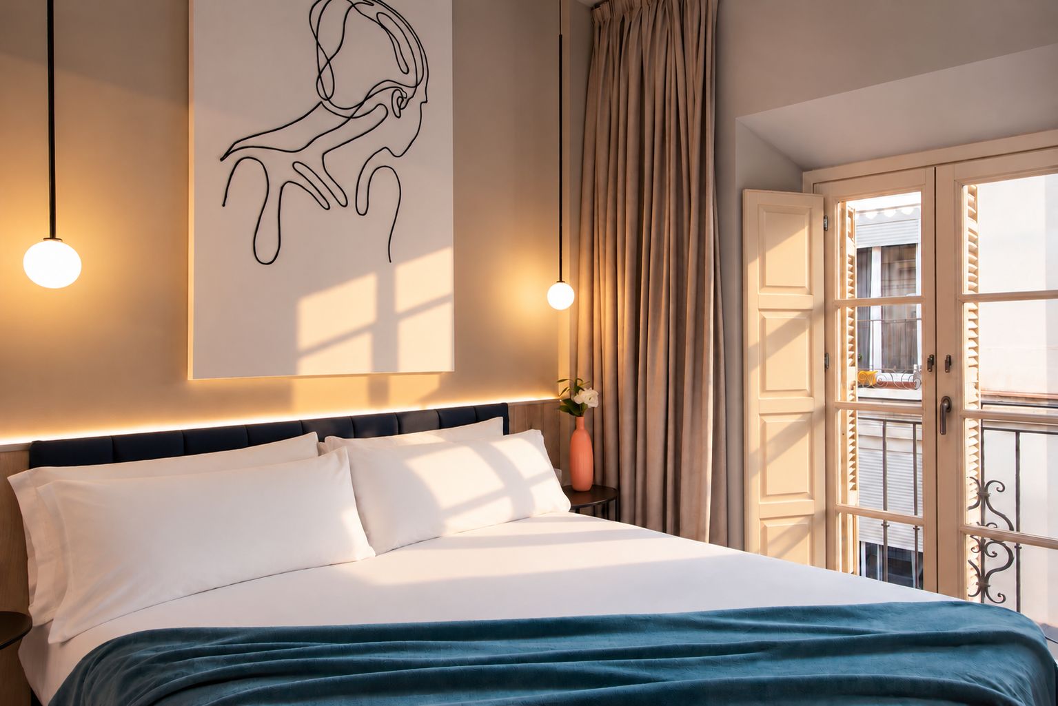 Una habitación de hotel con una cama, una obra de arte colgada en la pared, una ventana con cortinas y un balcón con barandilla.
