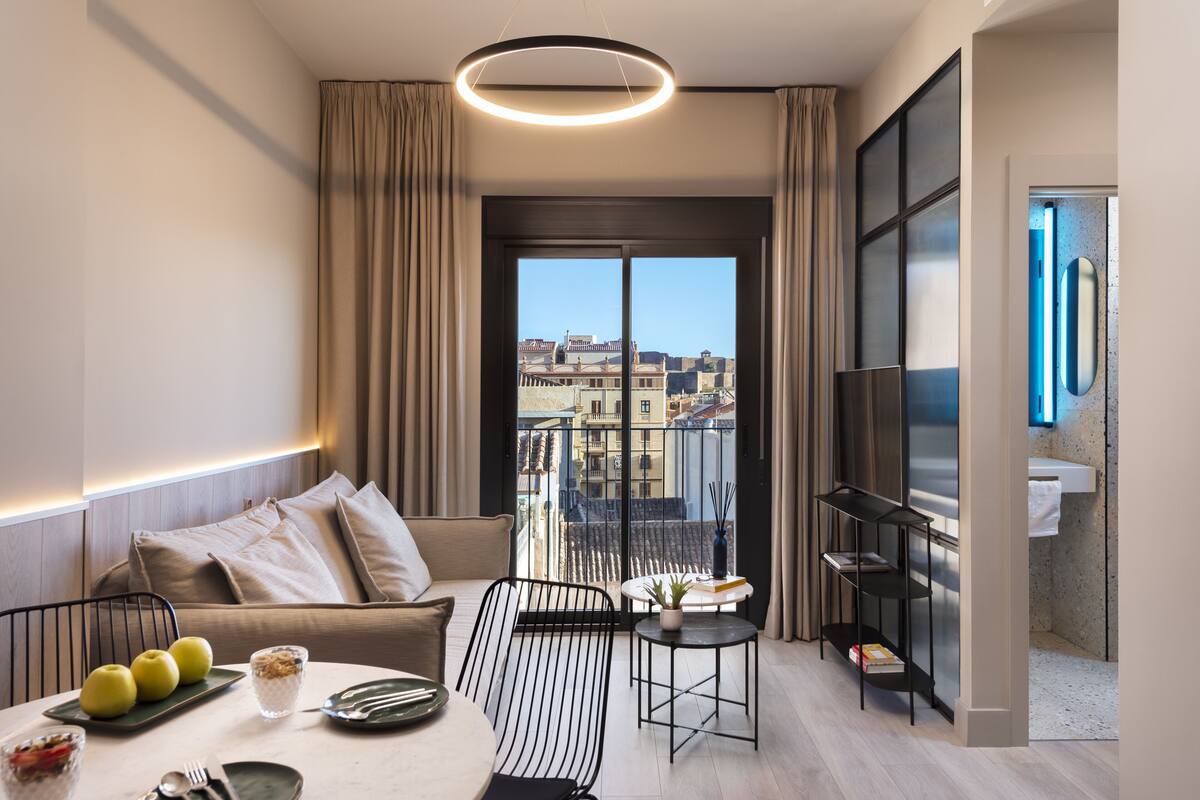 Uma sala de estar moderna com sofá, mesa de jantar e varanda com vista para a cidade.