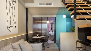 A modern living room with a sofa, a coffee table with magazines, and a staircase. - Coeo Peña Design Apartments (Málaga)