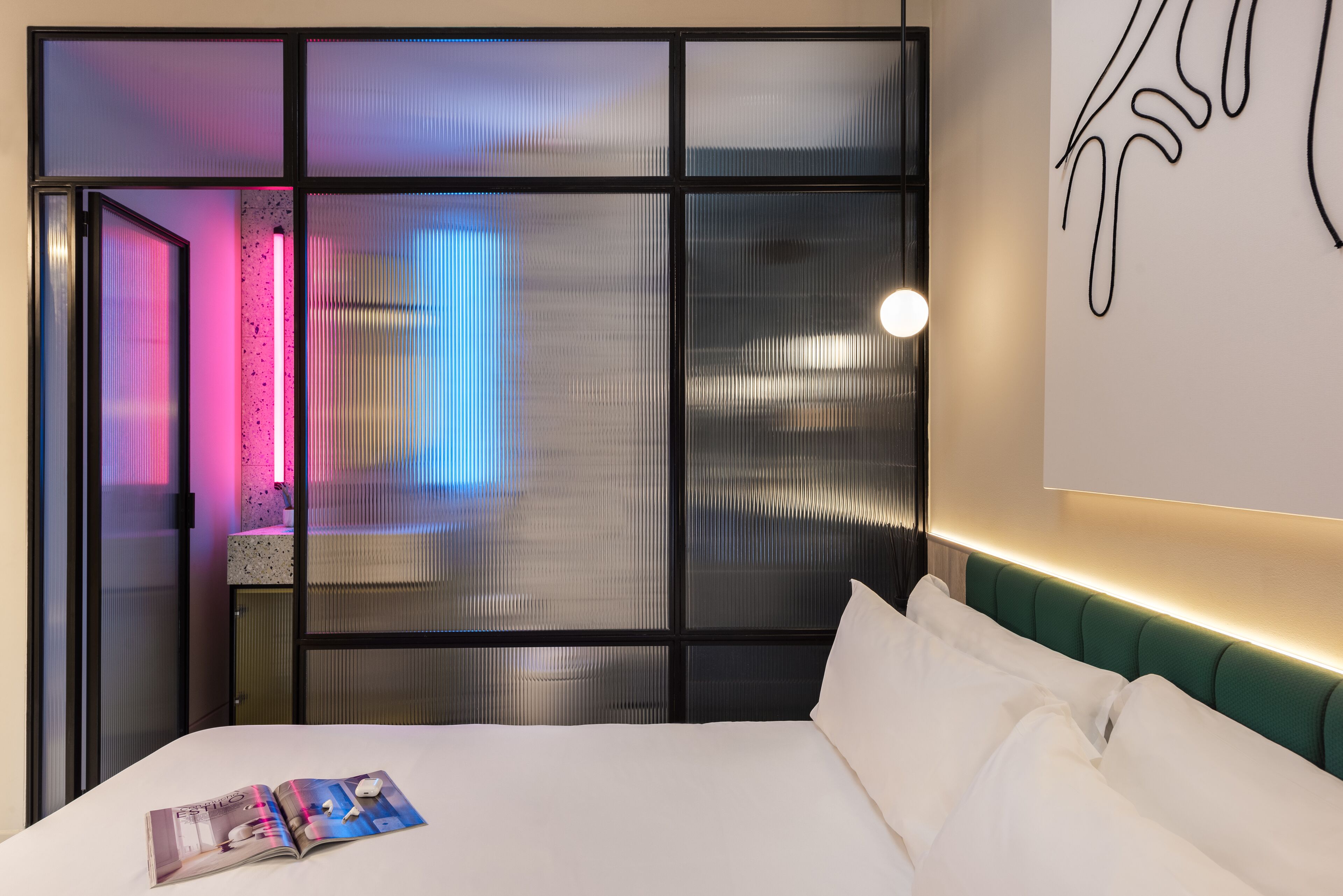 Una habitación de hotel moderna con una cama grande, una mesita de noche y una pared decorada con un dibujo lineal.